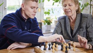 Ehrenamtler unterstützt Malteser Demenzdienste, indem er mit einer Seniorin Schach spielt.